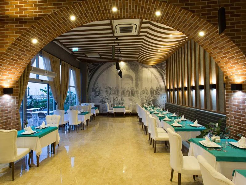 Salle de restaurant élégante avec tables dressées et murs en briques apparentes.