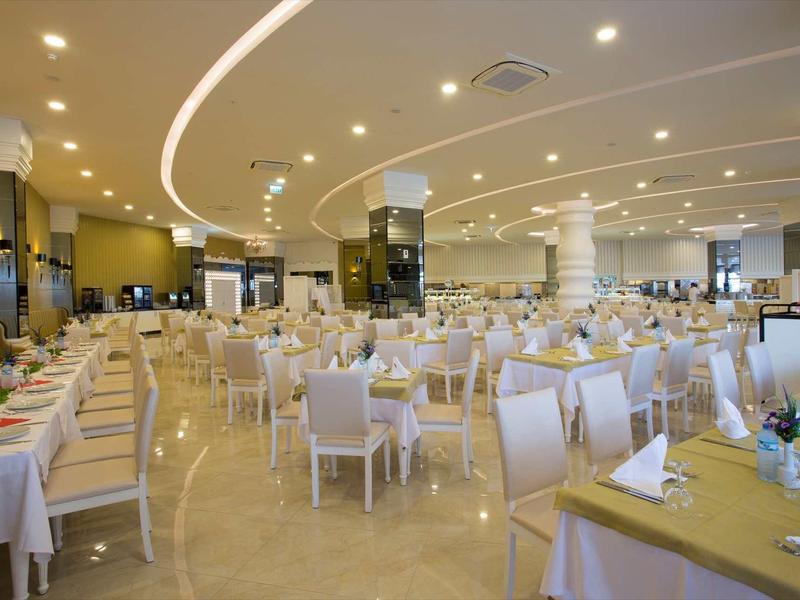 Grande salle de restaurant élégante avec tables garnies et chaises blanches.