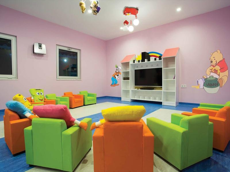 Salle colorée pour enfants avec fauteuils et tapis bleu dans un hôtel.