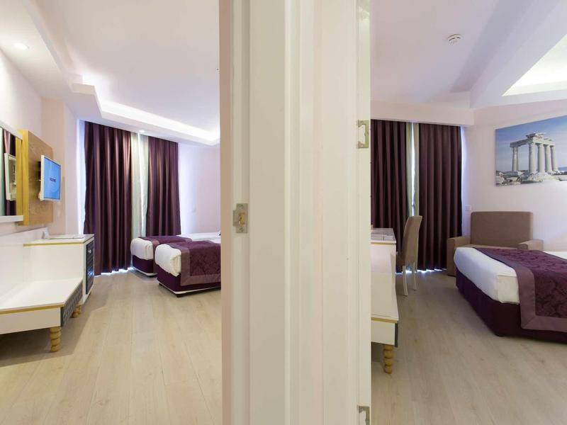 Chambres d'hôtel modernes séparées par un mur, lits doubles et rideaux foncés.