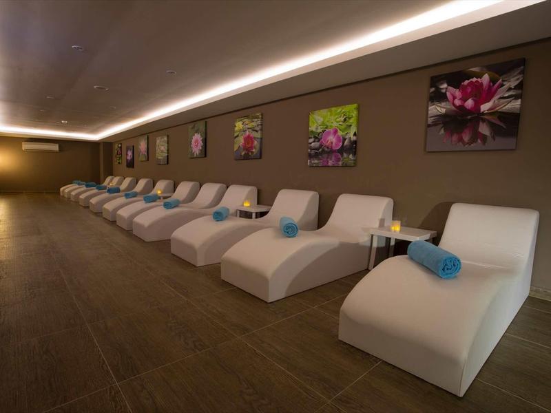 Ligne de chaises longues blanches avec serviettes bleues dans un spa élégant et lumineux.