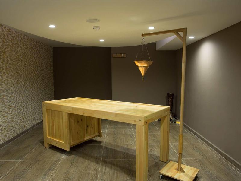 Bureau en bois clair dans une pièce minimaliste avec murs gris et motif sur un mur.