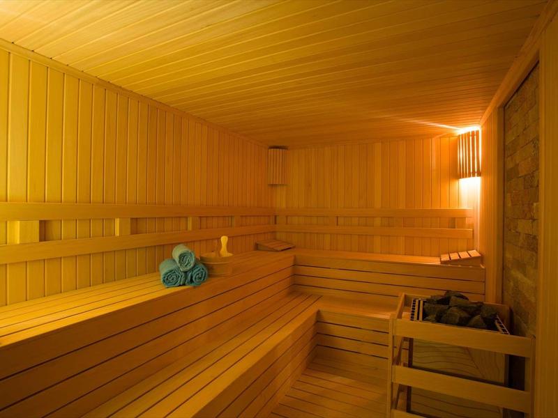 Intérieur d'un sauna en bois clair avec serviettes bleues pliées sur un banc.
