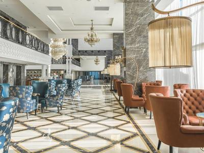 Elegant hotel lobby with comfortable armchairs, blue floral chairs, and chandeliers