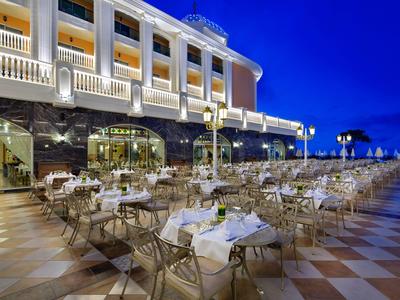 Large hotel terrace with set tables and chairs at dusk.