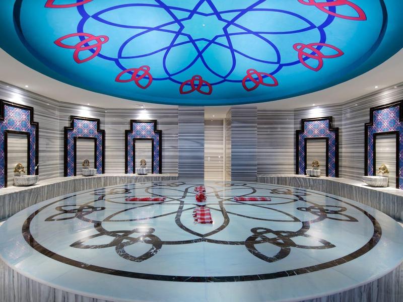 Elegant Turkish bath area with artistic ceiling design and seating along the walls.