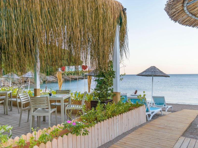 Beachside restaurant with straw umbrellas and a clear sky sea view.