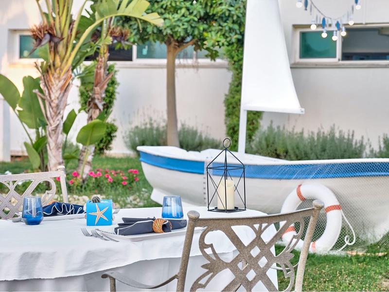 A table with drinks and gifts in the garden next to a boat and plants.