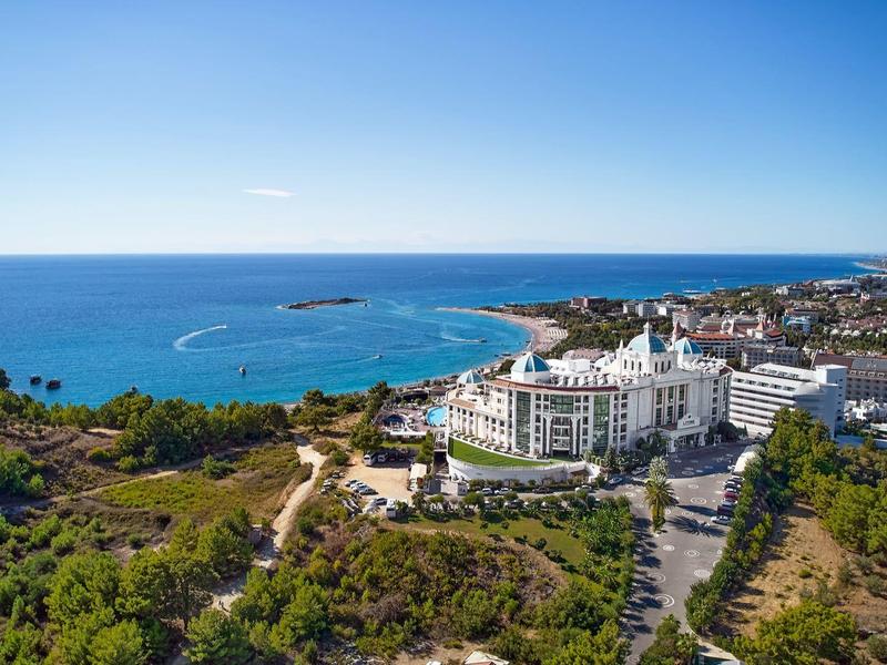 Seaside hotel complex with white building and lush greenery around under clear sky