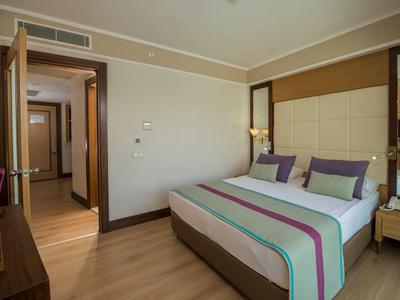 Gemütliches Schlafzimmer mit Doppelbett, Holzboden, Nachttisch und offenem Türrahmen zur Diele.