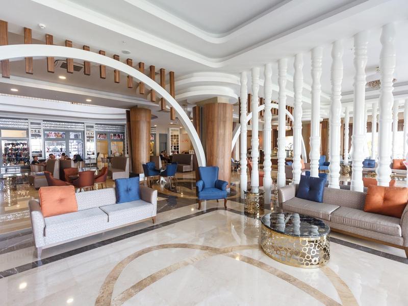 Großer, heller Hotel-Lobbybereich mit modernen Sofas, farbigen Kissen und Marmorboden.