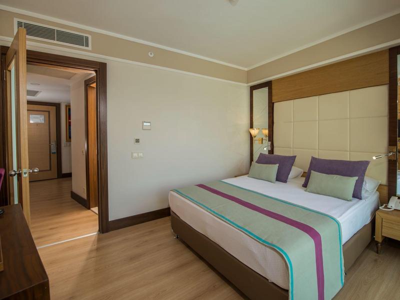 Gemütliches Schlafzimmer mit Doppelbett, Holzboden, Nachttisch und offenem Türrahmen zur Diele.