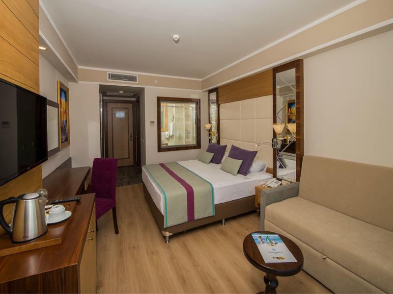 Modern eingerichtetes Hotelzimmer mit Doppelbett, Fernseher und gemütlicher Sitzecke.