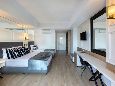 Modern eingerichtetes Hotelzimmer mit großem Bett, Spiegel, Schreibtisch und hellen Holzböden.