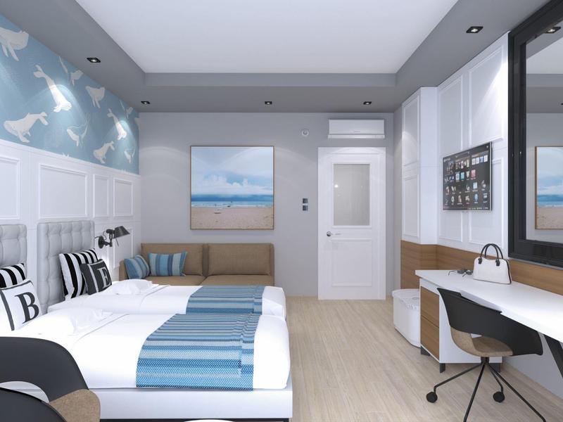 Modernes Schlafzimmer mit zwei Betten, blauer Wandtapete, Schreibtisch und großem Spiegel.