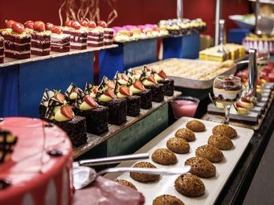 Buntes Buffet mit verschiedenen Tortenschnitten und Desserts auf weißen Tellern und Etageren.