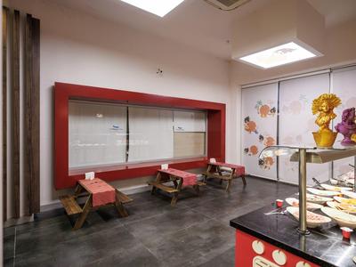 Moderner Ausstellungsraum mit Glasvitrinen, bunten Figuren und rotem Möbelstück an weißer Wand.