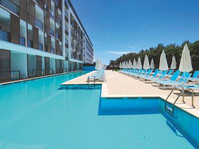 Moderner Außenpool mit glattem, blauem Wasser, blauen Liegestühlen und weißen Sonnenschirmen.