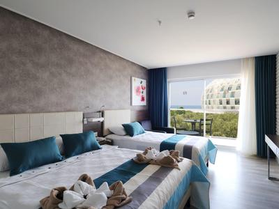 Modernes Doppelzimmer mit zwei Betten, blauen Kissen, großen Fenstern und ruhiger Außensicht.