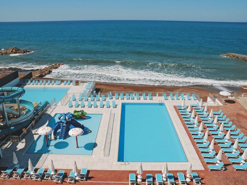 Hotelová bazénová plocha s lehátky a slunečníky přímo u moře