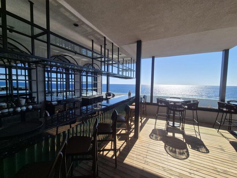 Terasa s stoly a židlemi s výhledem na moře za slunečného počasí