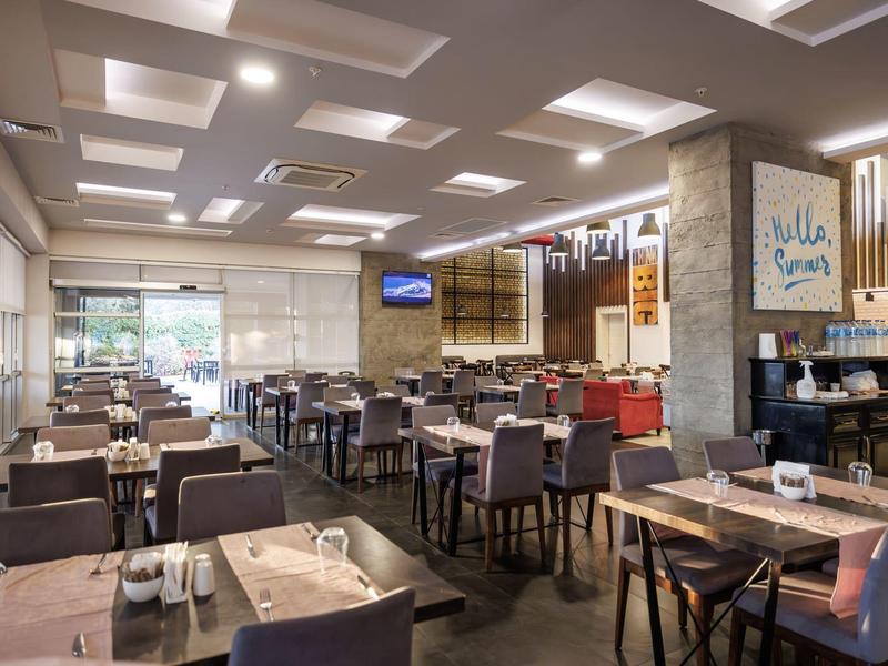 Moderní restaurace s prostřené stoly a velkými okny umožňujícími denní světlo.