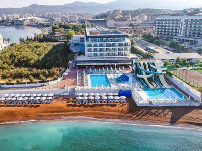 Luxusní hotel s bazénem, vodními skluzavkami a přímým přístupem na pláž s deštníky.