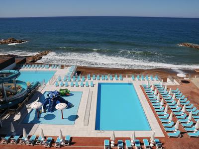 Hotelový bazén s lehátky s výhledem na moře za slunečného dne