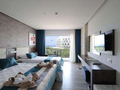 Moderní hotelový pokoj se dvěma postelemi, balkonem a výhledem na moře za denního světla.