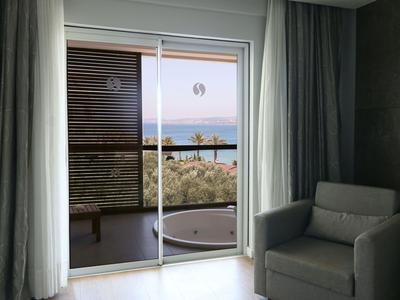 Hotelový pokoj s křeslem a výhledem na balkon s vanou a mořem