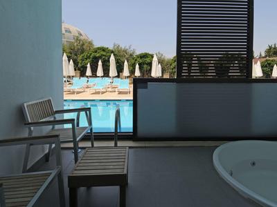 Výhled z terasy s vířivkou na bazén a lehátka s deštníky.