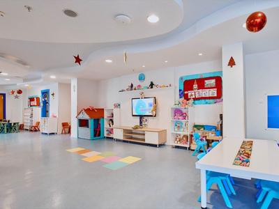 Kleurrijke speelruimte met tafels, stoelen en wanddecoraties in een hotel of vakantiehuis.