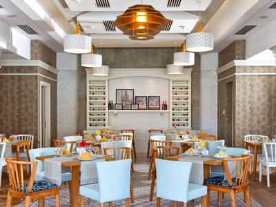 Restaurant mit gemischten Holz- und weißen Stühlen, runden Tischen, modernen Lampen und hellem Interieur.