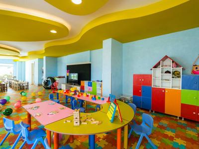 Bunter Kindergartenraum mit blauen Stühlen, bunten Tischen, Spielzeug und farbenfrohen Schränken.