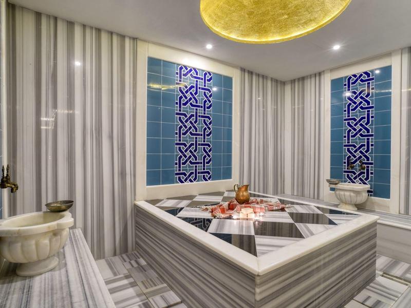 Luxe Turks hammam met marmeren zitplaatsen en gedetailleerde blauwe tegels.