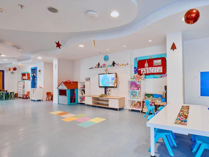 Kleurrijke speelruimte met tafels, stoelen en wanddecoraties in een hotel of vakantiehuis.