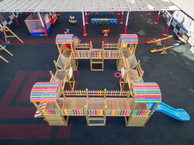 Kleurrijke speeltuin met kasteeltorens en glijbanen op zachte ondergrond.