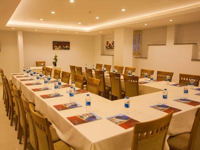 Großer, heller Konferenzraum mit U-förmigem Tisch, weißen Tüchern, Stühlen und Wasserflaschen.