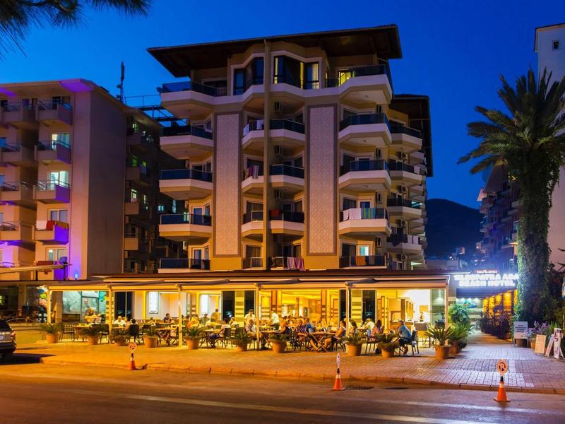 Modernes Hotelgebäude mit beleuchtetem Außenbereich und Palmen bei Abenddämmerung.
