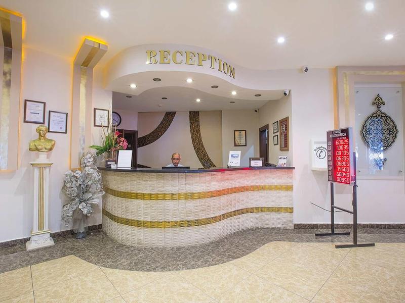 Helle Hotellobby mit geschwungenem Empfangstresen, dekorativen Pflanzen und Beleuchtung.