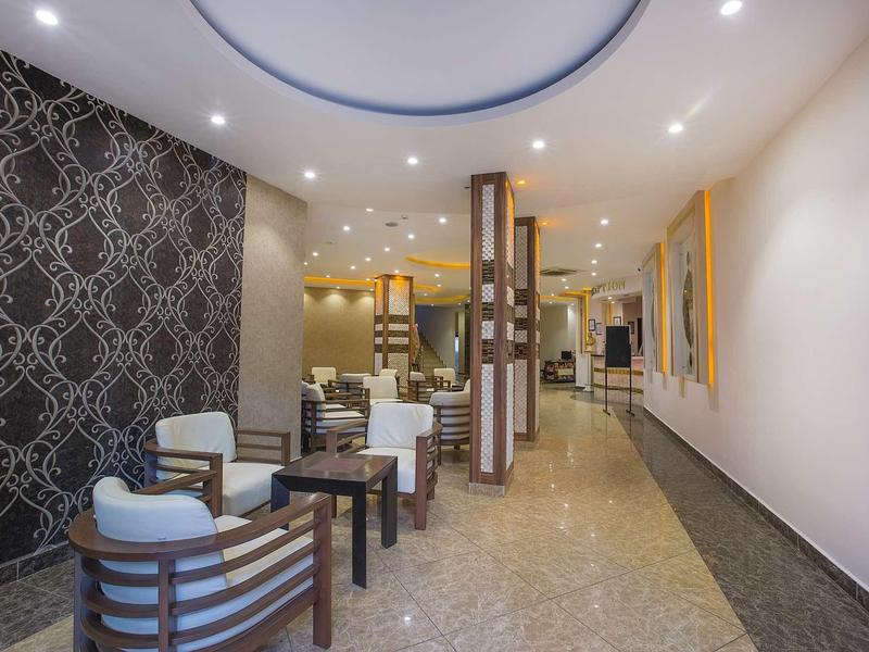 Moderner Wartebereich mit gemusteter schwarz-weißer Wand, mehreren Stühlen, Tischen und heller Beleuchtung.