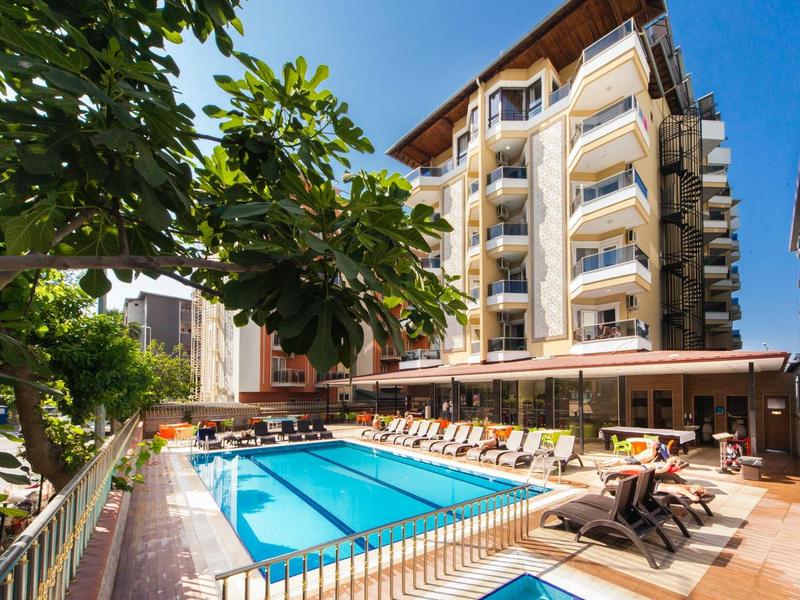 Ein großes Hotel mit mehreren Stockwerken neben einem klaren Außenpool bei sonnigem Himmel.