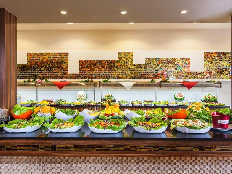 Großes Buffet mit verschiedenen frischen Salaten, Gemüse und Dressings auf Holztisch angerichtet.