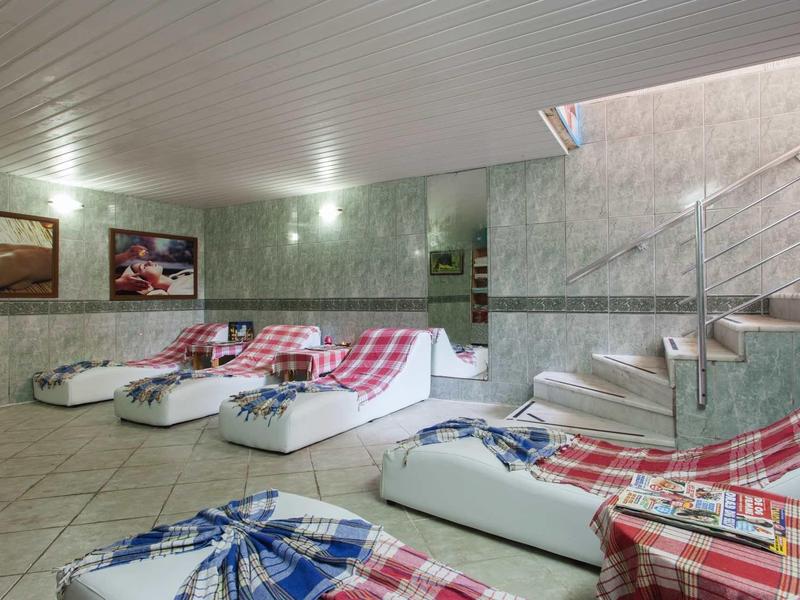 Relaxation room with white loungers and checkered blankets next to a staircase in a hotel.