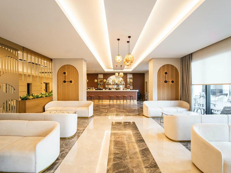 Moderní hotelová lobby s bílým čalouněným nábytkem a elegantním barem.