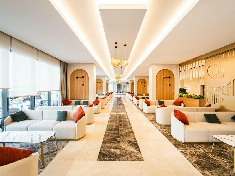 Velká moderní hotelová lounge s posezením, vysokými stropy a dostatkem přirozeného světla.