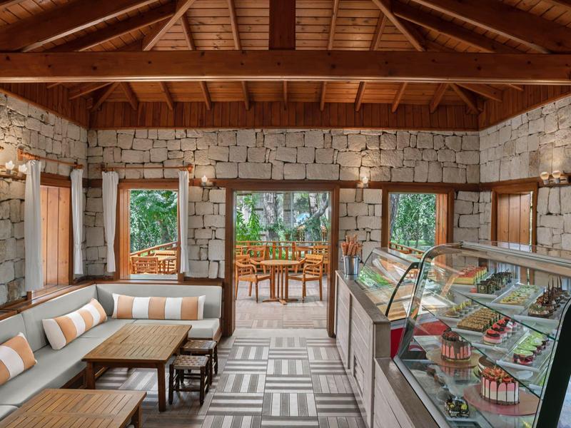 Cozy lounge area with stone walls, wooden ceiling, and a glass display case of desserts.