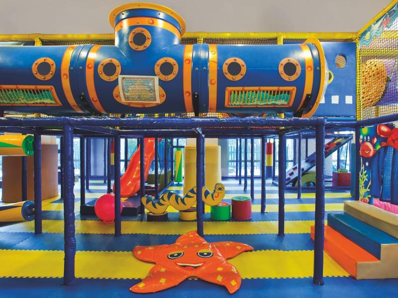 Water park area with multiple water slides and a pool surrounded by trees and lounge chairs.