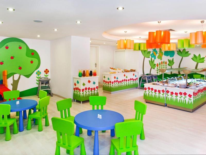 Bright and colorful children's playroom with green and blue furniture and playful wall murals.