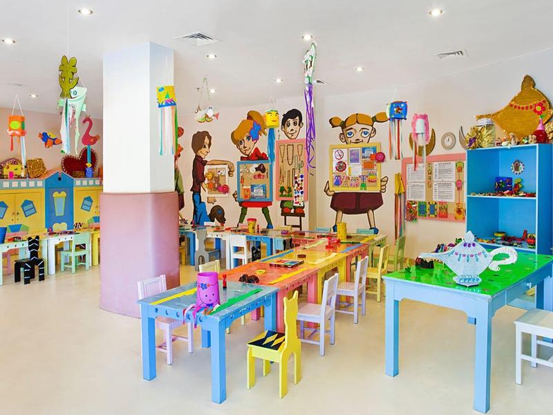 Resort with large blue pools surrounded by green trees and mountains in the background.